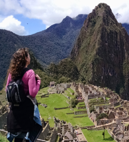 A woman with a backpack gazes at the ancient Incan ruins of Machu Picchu nestled in the Andes Mountains under a partly cloudy sky. A woman with a backpack gazes at the ancient Incan ruins of Machu Picchu nestled in the Andes Mountains under a partly cloudy sky.