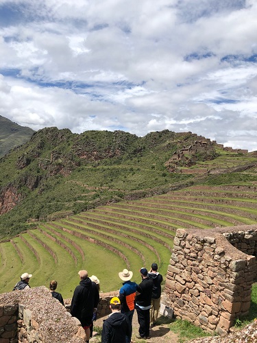 Tourists overlook ancient agricultural terraces set in lush green mountains under a partly cloudy sky. Tourists overlook ancient agricultural terraces set in lush green mountains under a partly cloudy sky.
