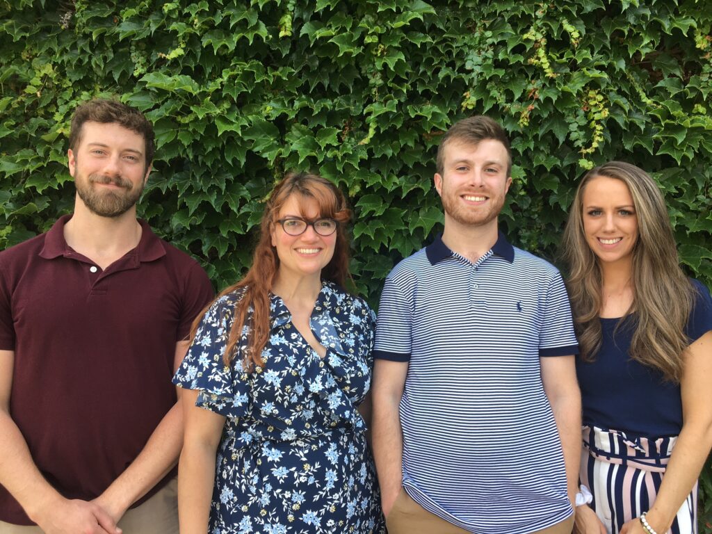 Four alumni stand with each other.