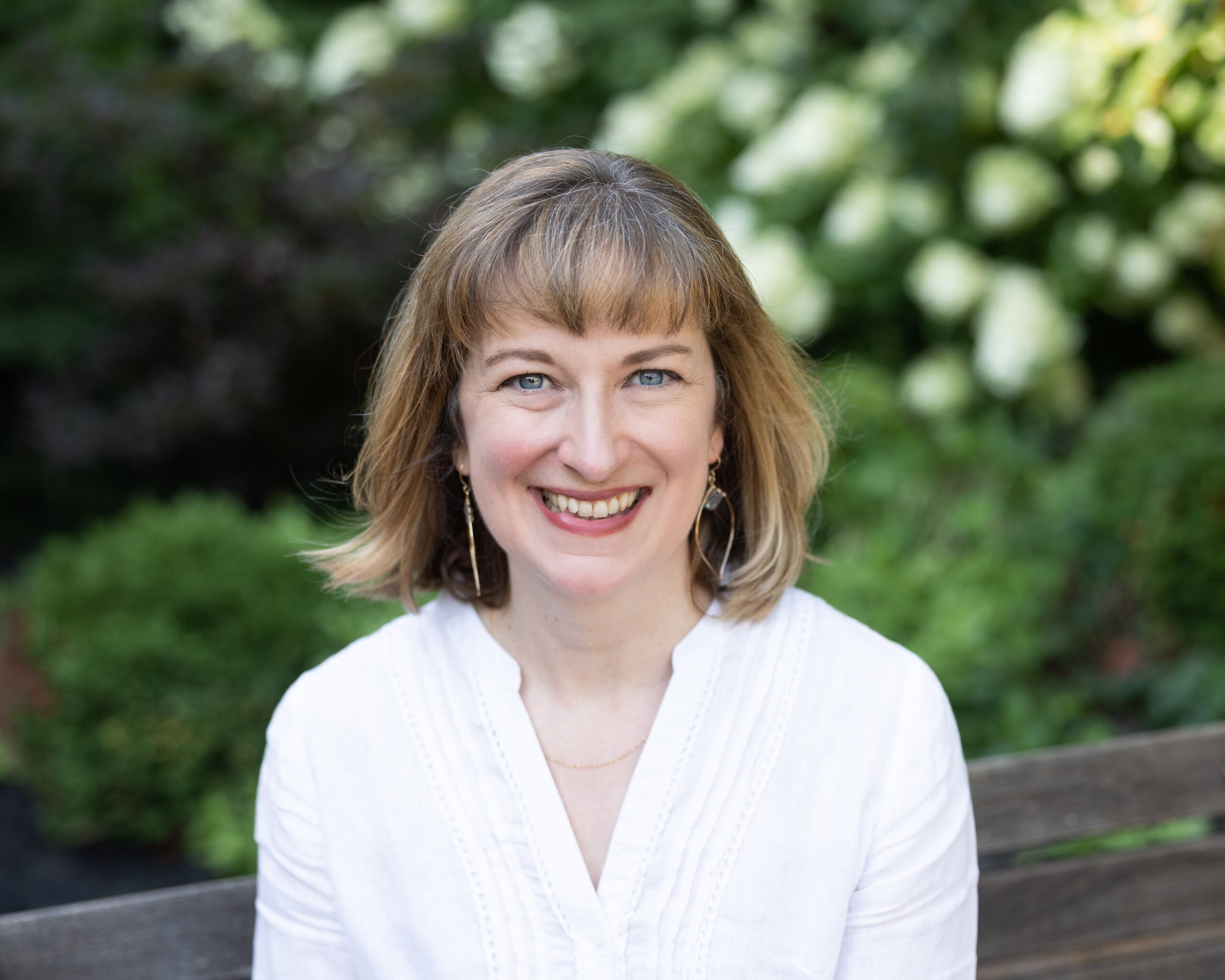Alice Rutkowski sits on a bench outside in a white shirt