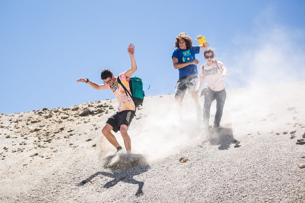 Students sliding down a hill of pebbles.