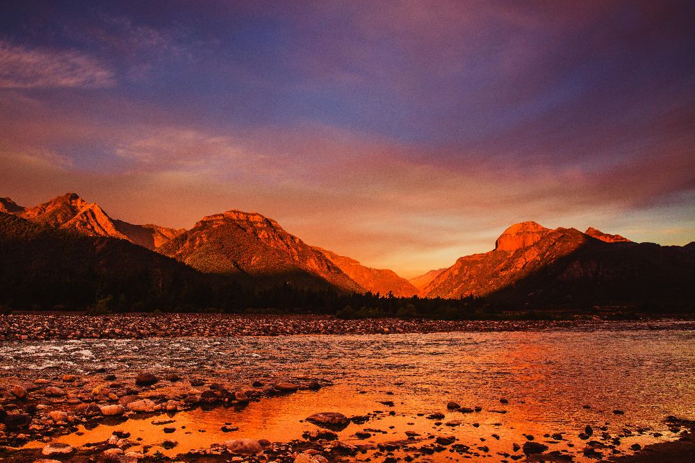 A sunset filled ladscape with a ridge and stream.