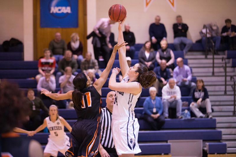 A SUNY Geneseo women's basketball player catching the ball while guarded by another player A SUNY Geneseo women's basketball player catching the ball while guarded by another player