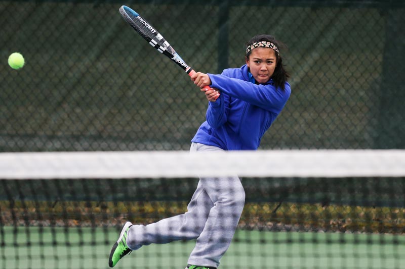 A SUNY Geneseo tennis player lobs the ball across the net. A SUNY Geneseo tennis player lobs the ball across the net.