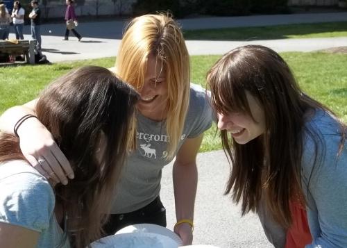three students with pies laughing