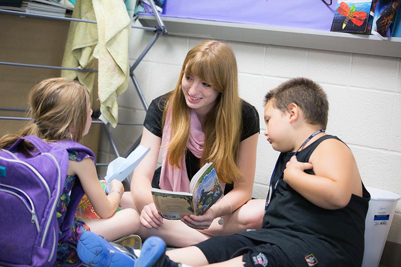childhood-with-special-education-geneseo-student-reading-to-kids student reading to young children
