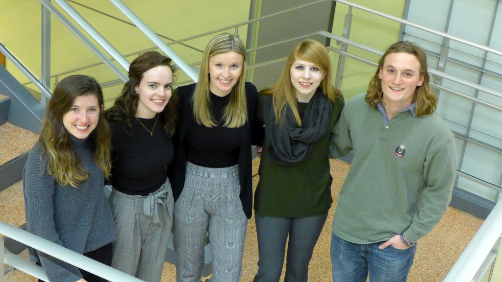 Five students standing together and smiling Five students standing together and smiling