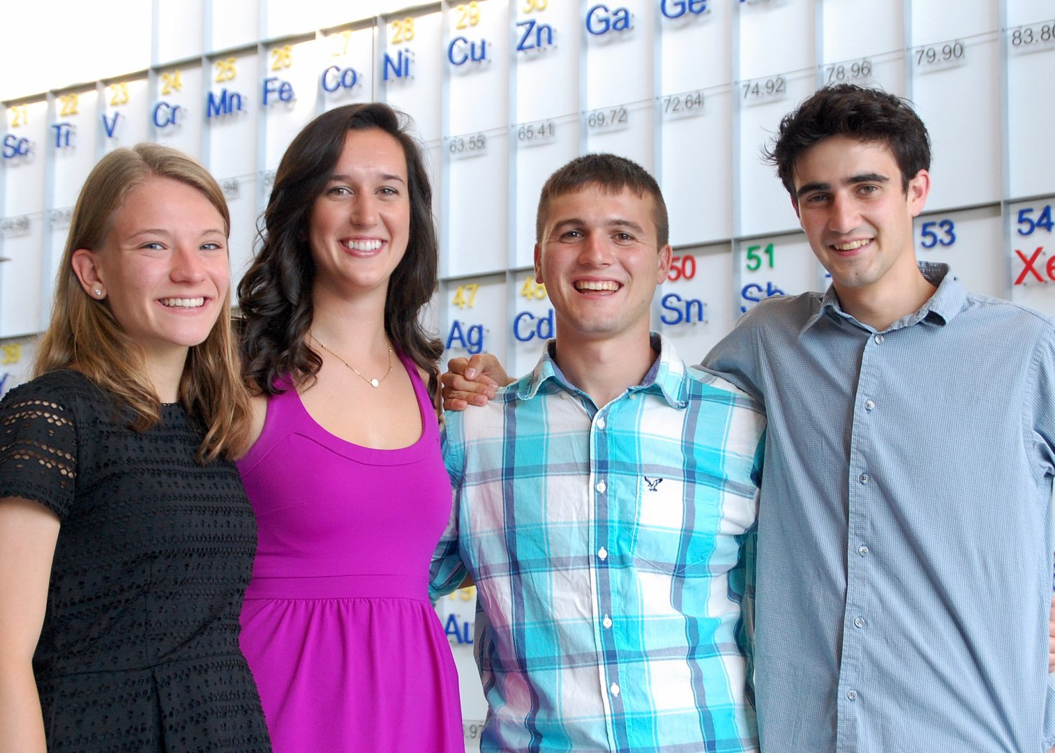 Four students standing together and smiling Four students standing together and smiling