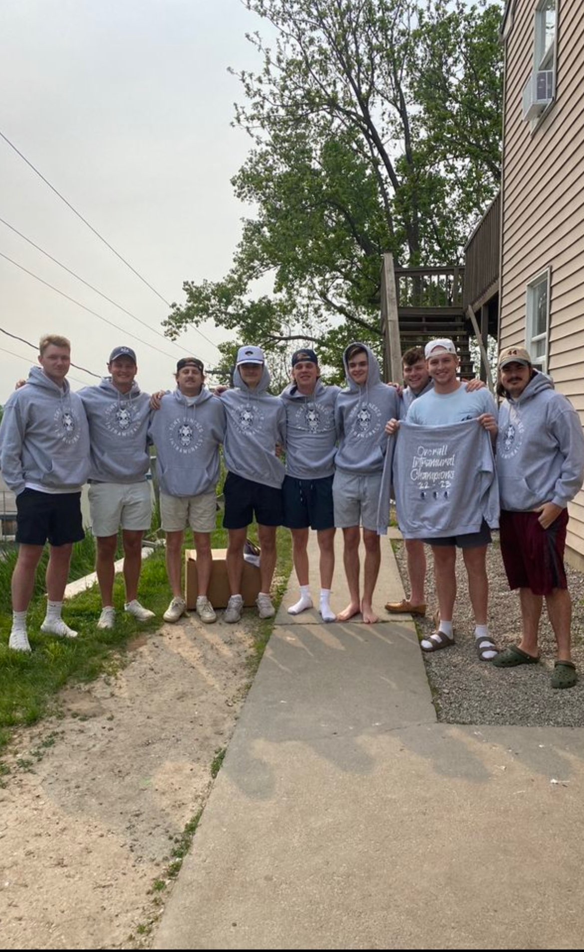 Eight athletes wearing gray uniforms and standing together outside Eight athletes wearing gray uniforms and standing together outside