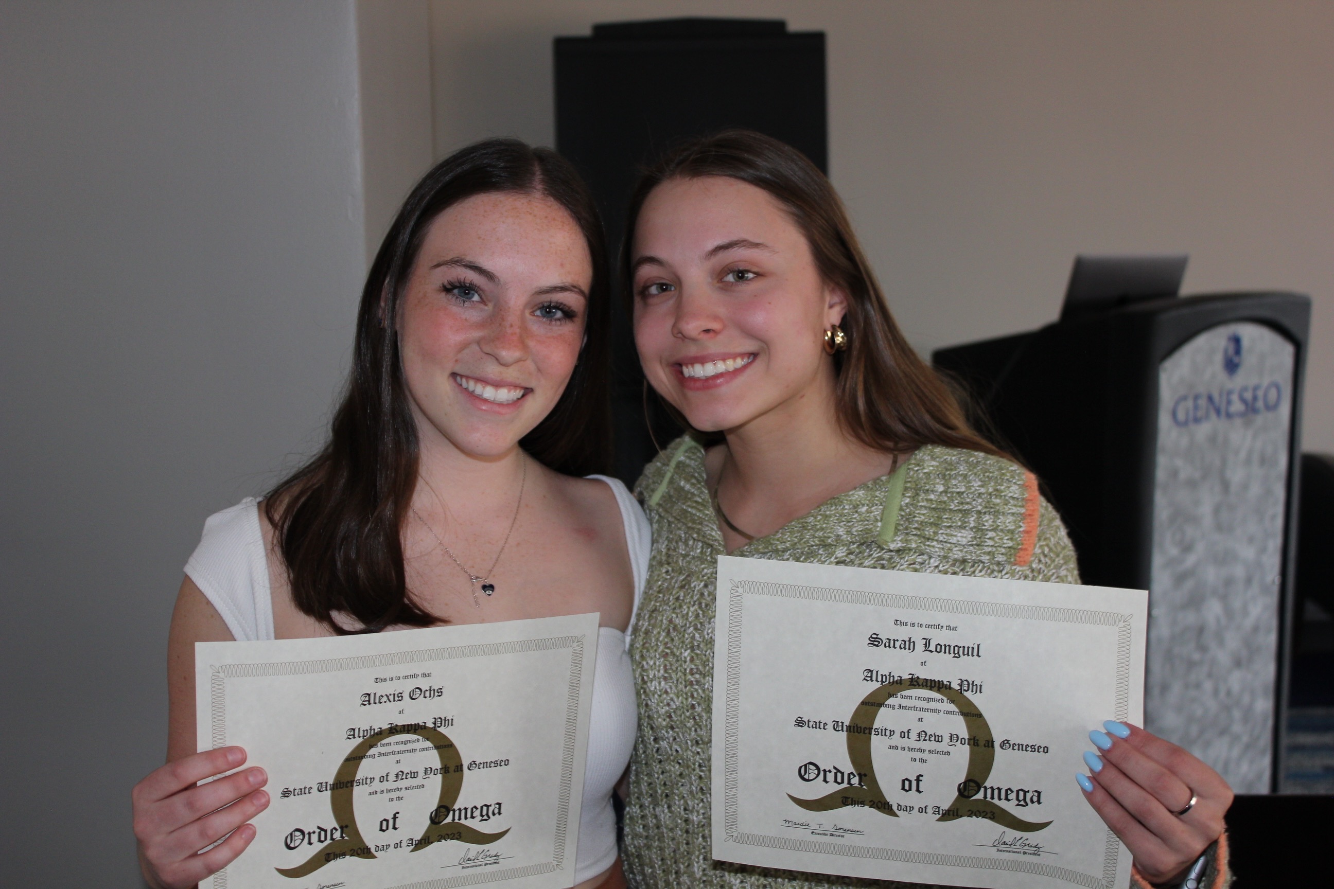 Two members holding their Outstanding Interfraternity Contributions certificates