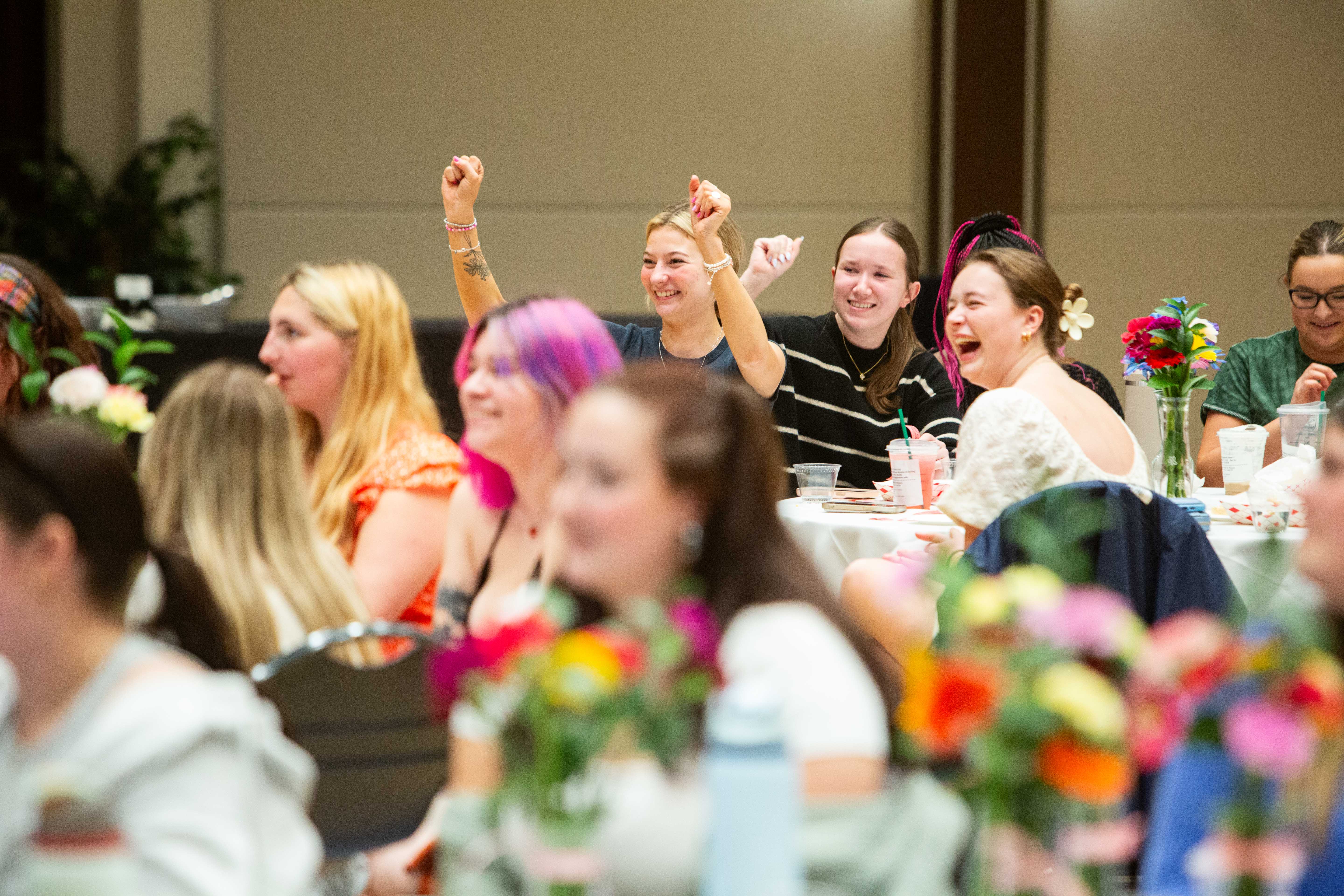 Students sitting at tables and cheering.