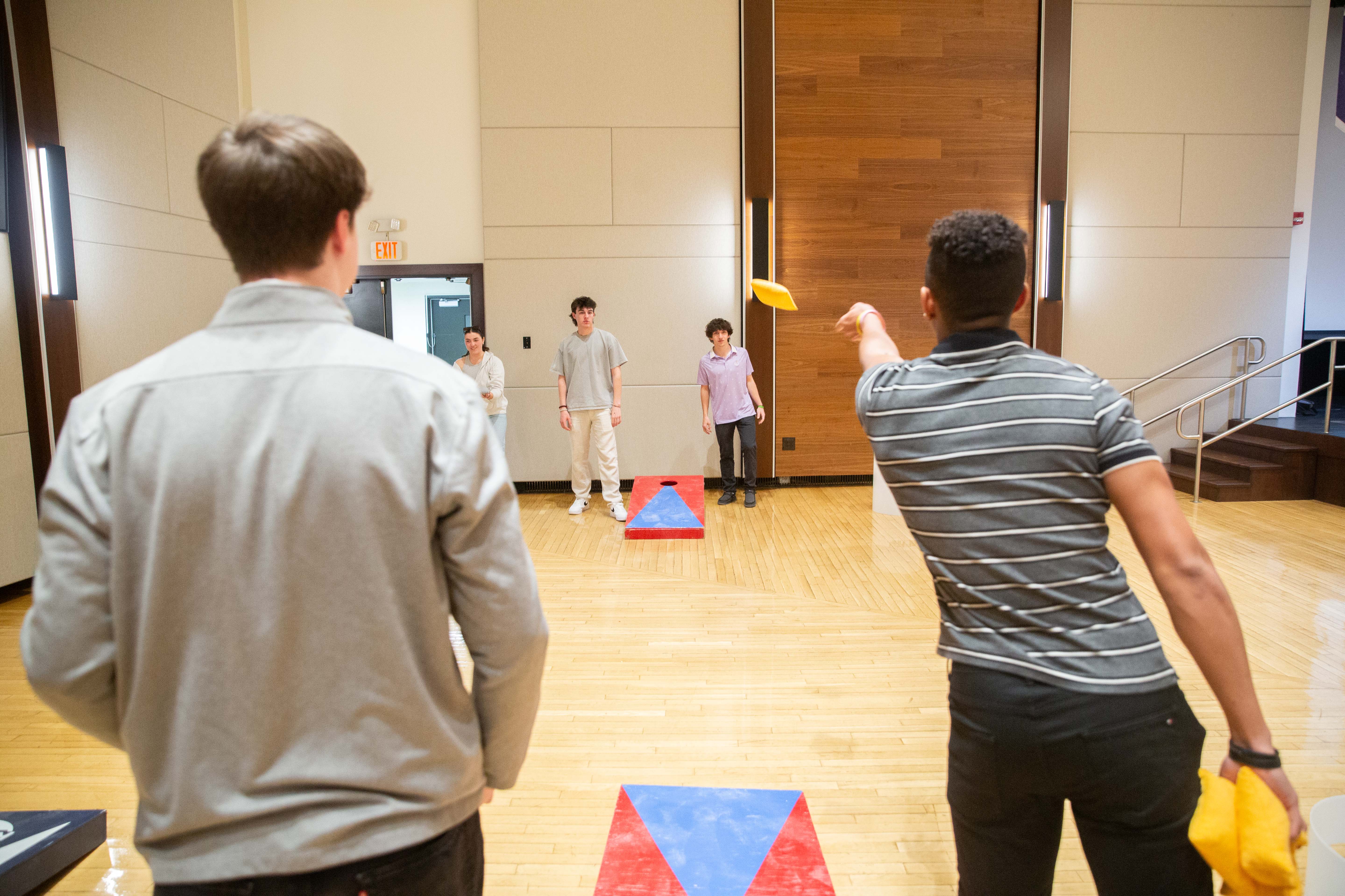 Students playing cornhole indoors.