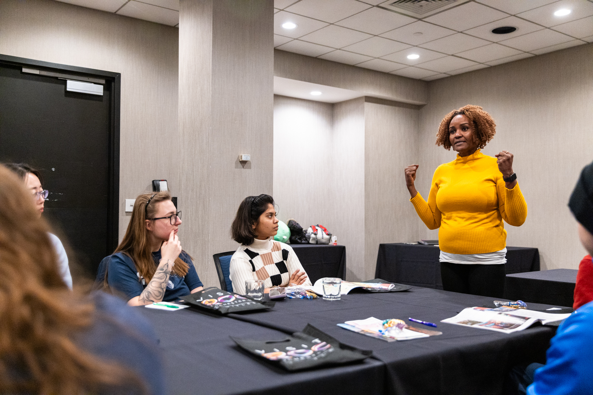 A student standing and speaking to a table of other students.