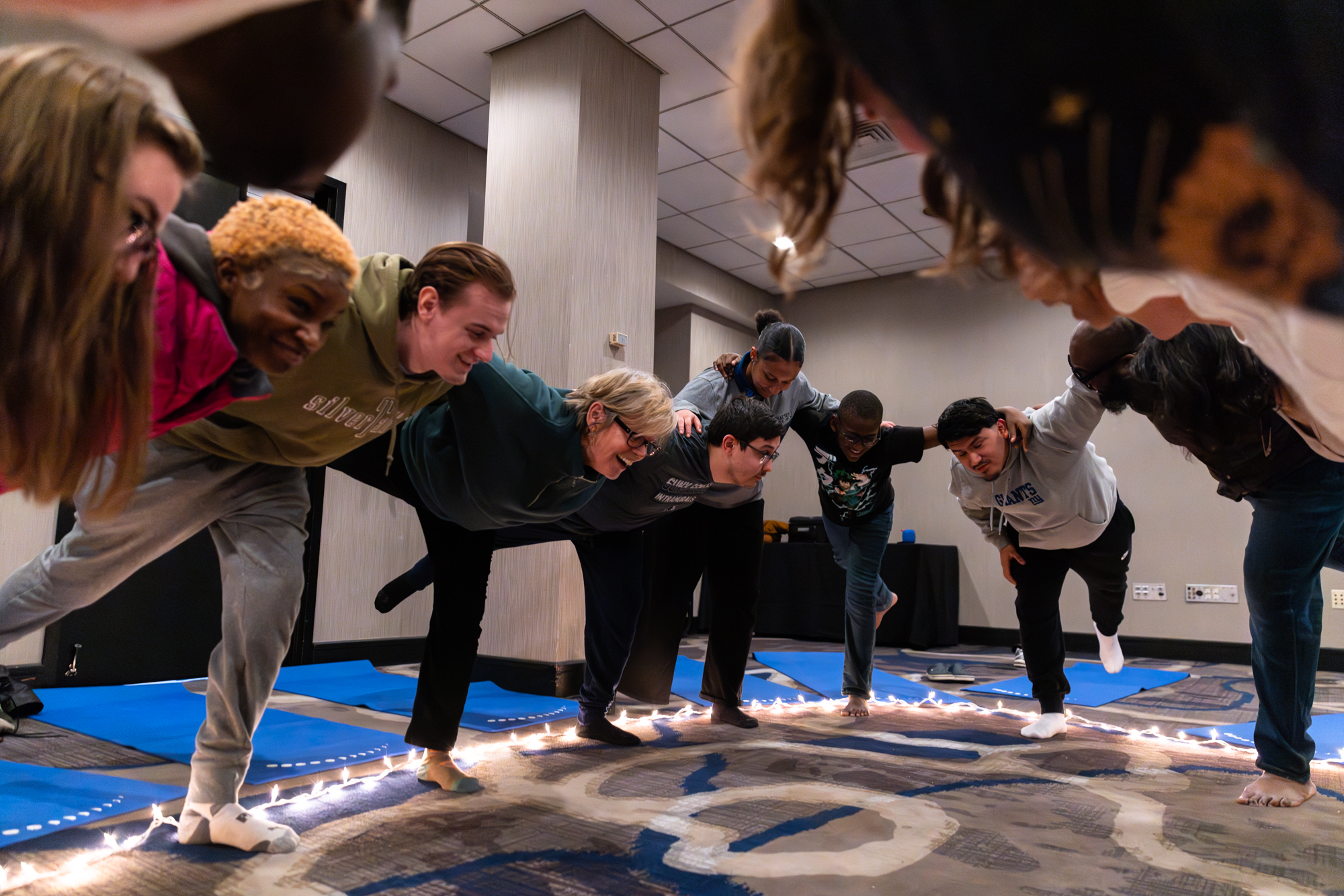 Group of students holding each other while standing on one leg.