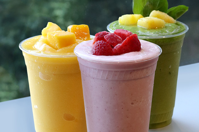 Three vibrant smoothies topped with fruit.