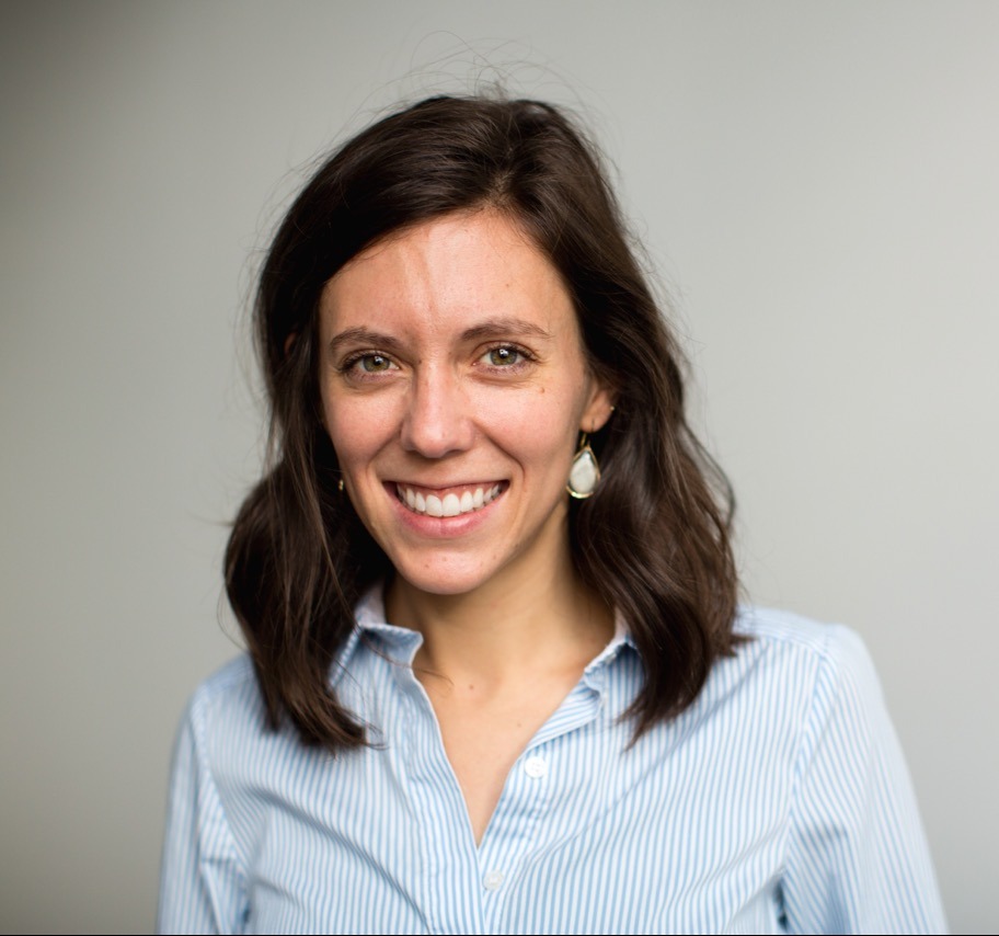 Woman with long brown hair wearing a blue shirt, smiling