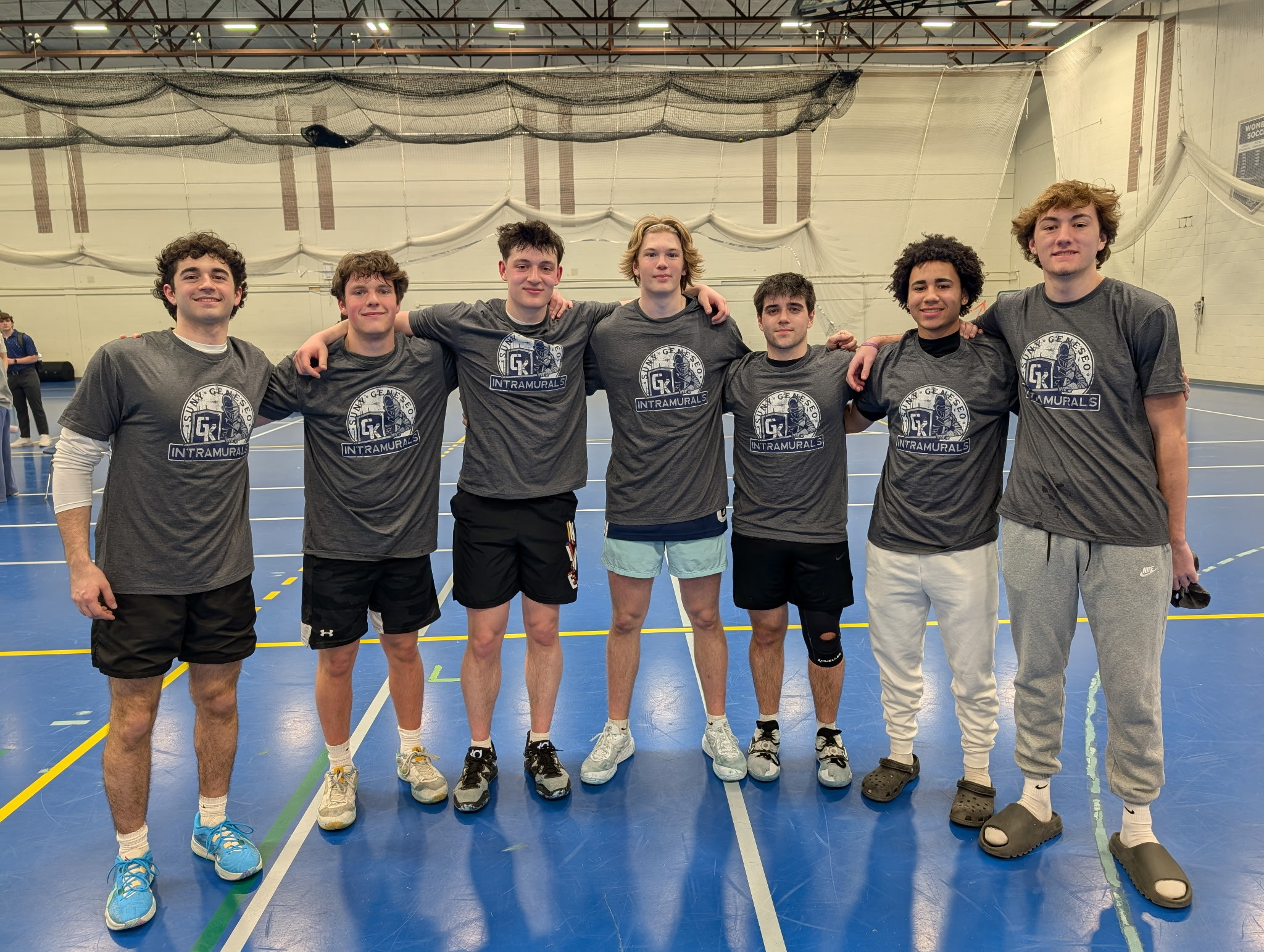 group of students standing side by side, wearing grey intramural shirts, in kuhl gym