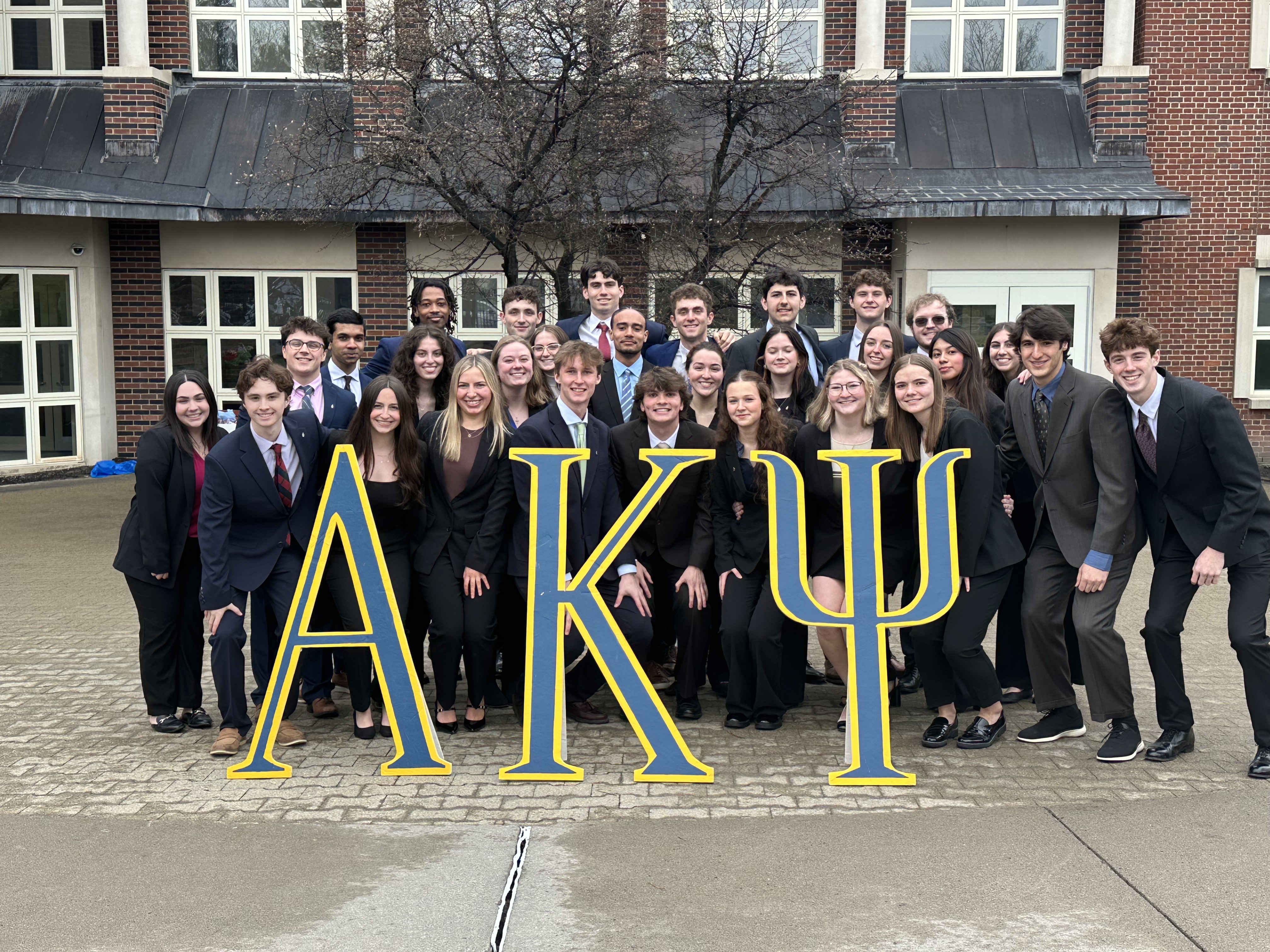 Alpha Kappa Psi students holding large AKP letters.