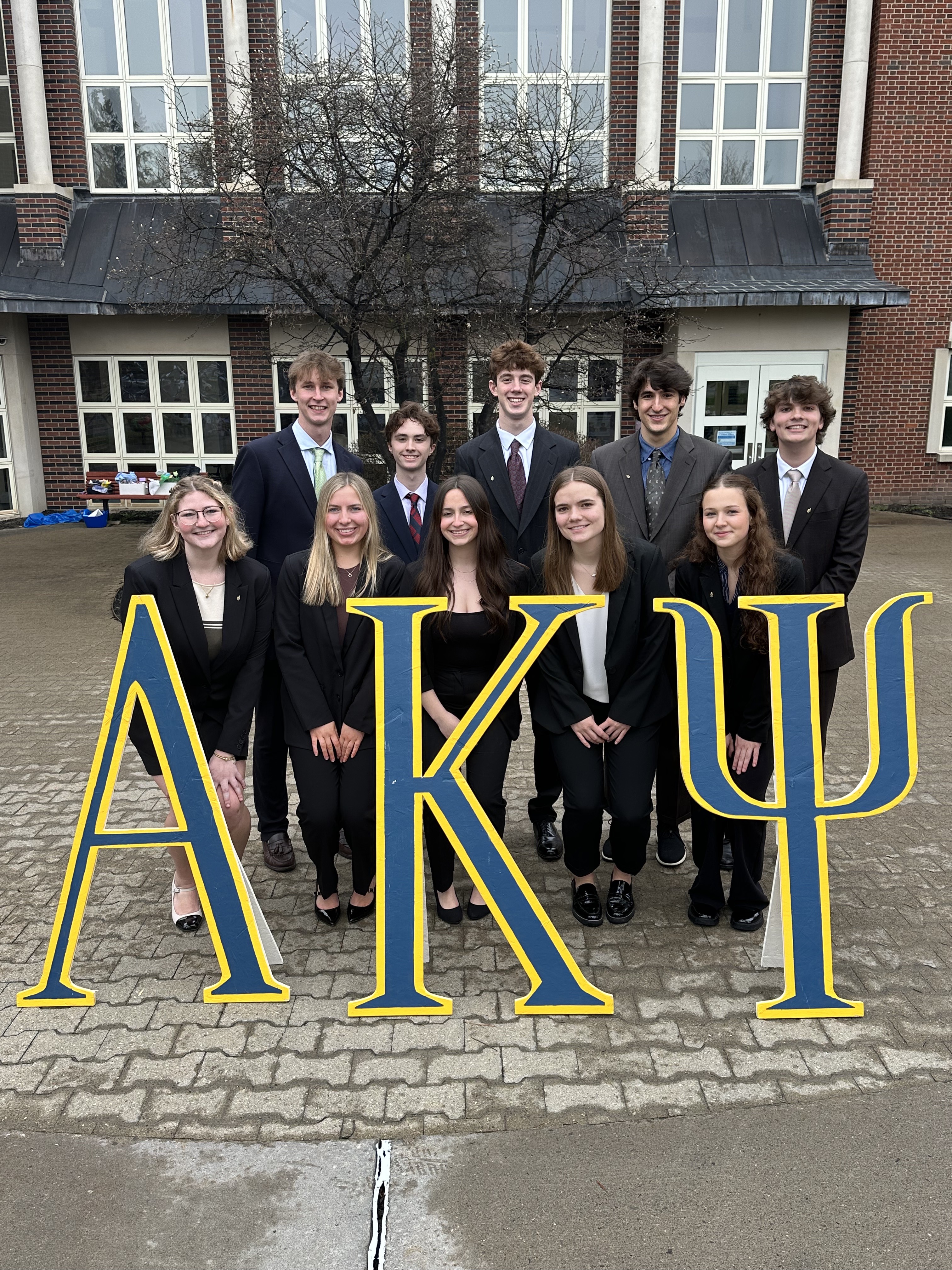 Alpha Kappa Psi students holding large AKP letters.