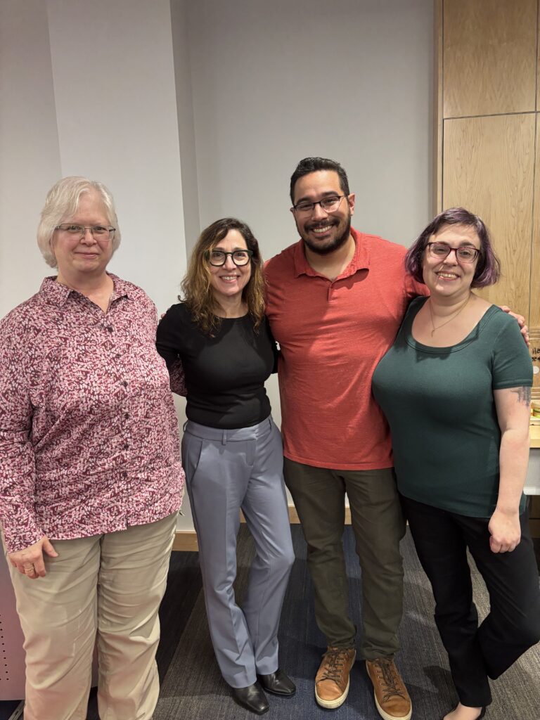 Four Sociology professors smiling and posing for a group photo indoors.