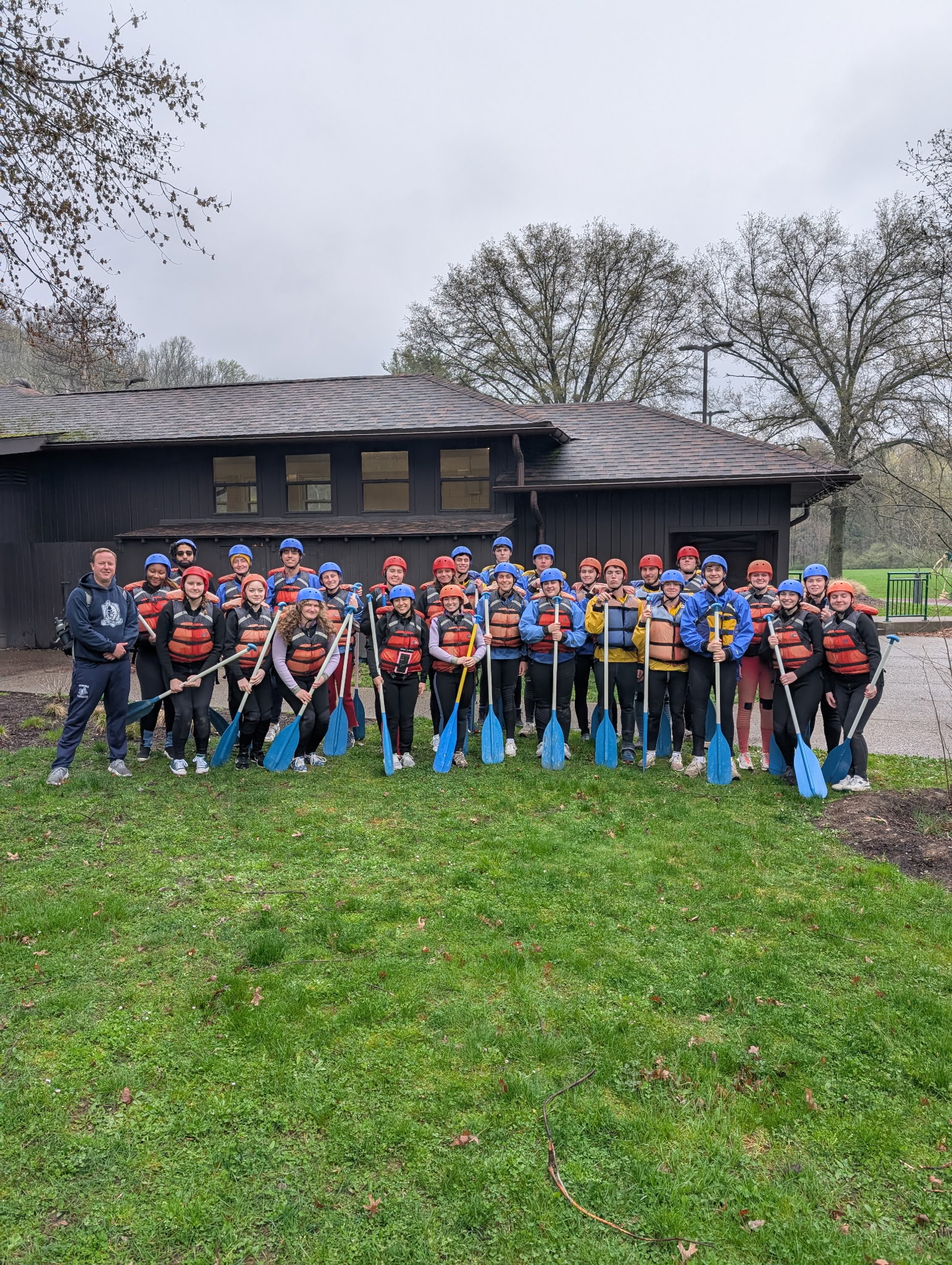 Group of students together outside, wearing life vests, helmets, and carrying orrs