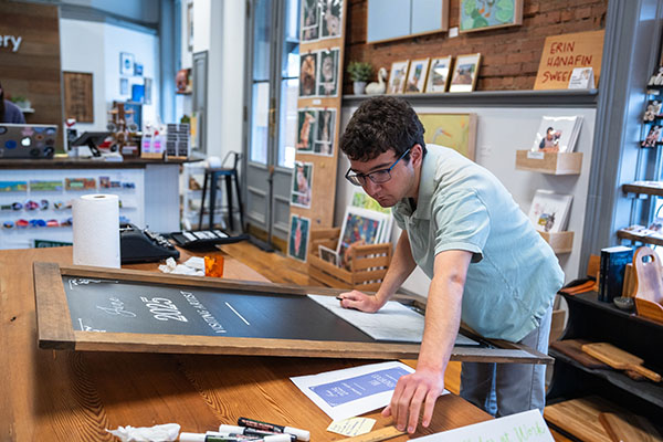 Zachary Mogavero chalking on a sign board