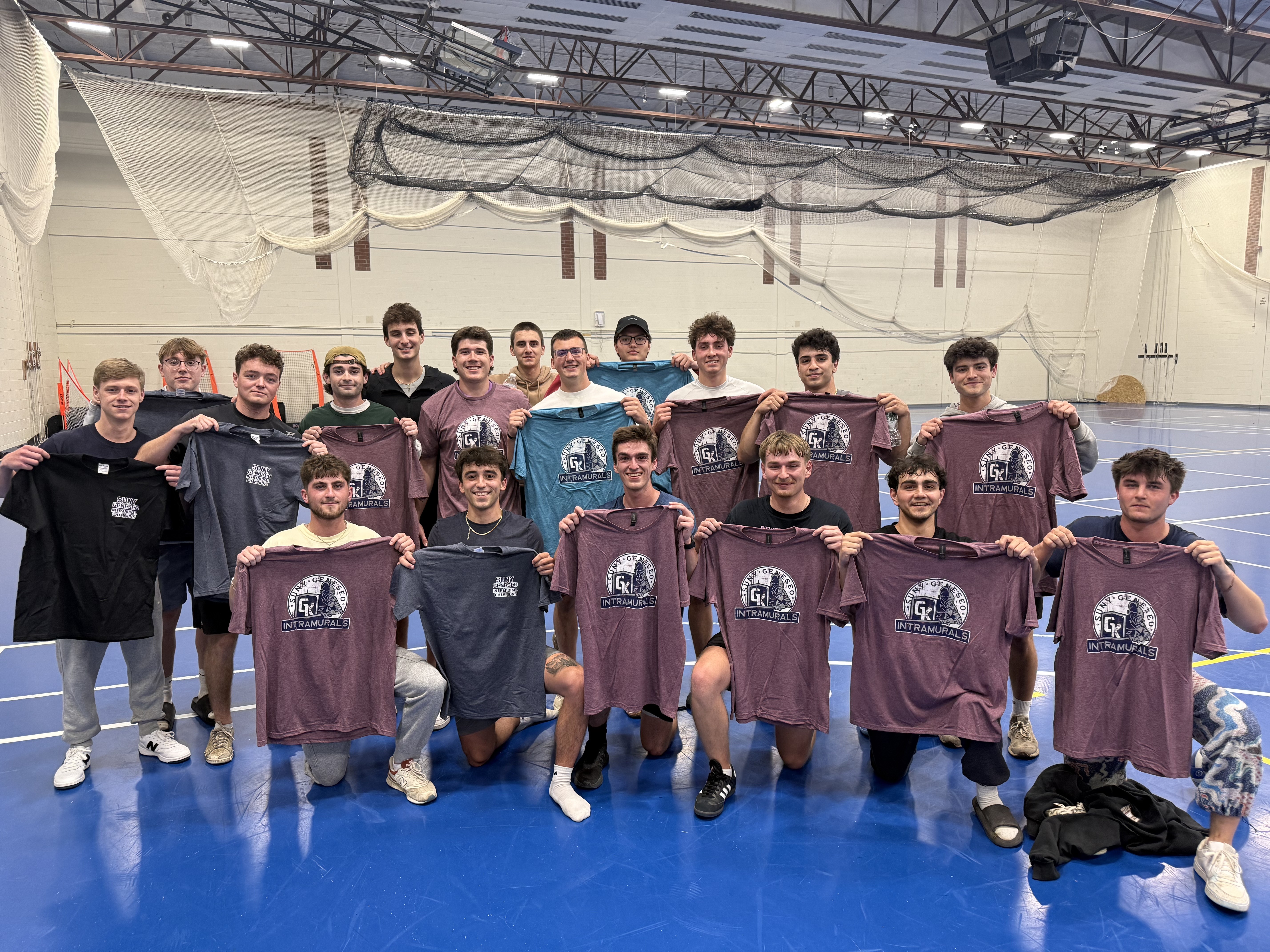 group of students in kuhl gym holding up maroon champ shirts
