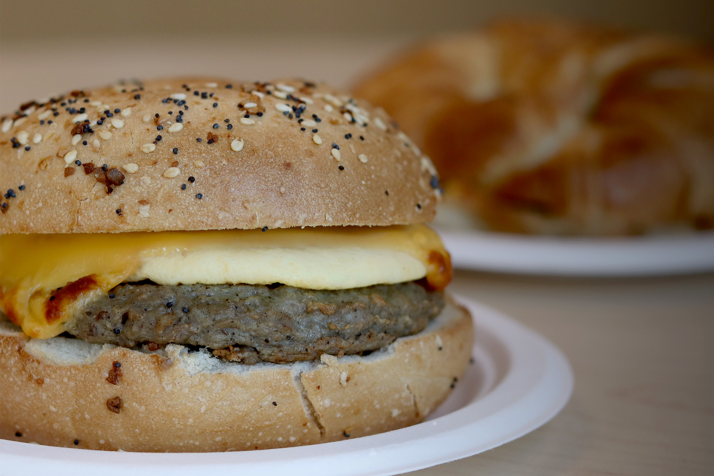 Breakfast sandwich with sausage, egg, and cheese on an everything bagel.