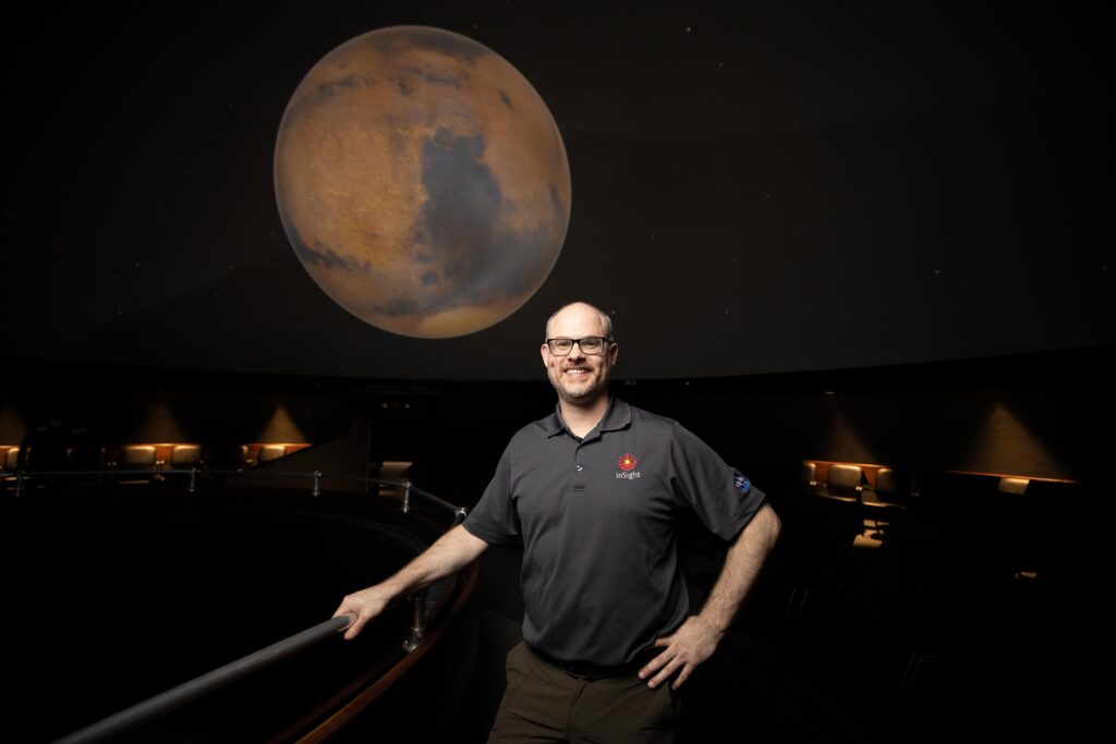 Nicholas Warner '00 in front of an image of Mars