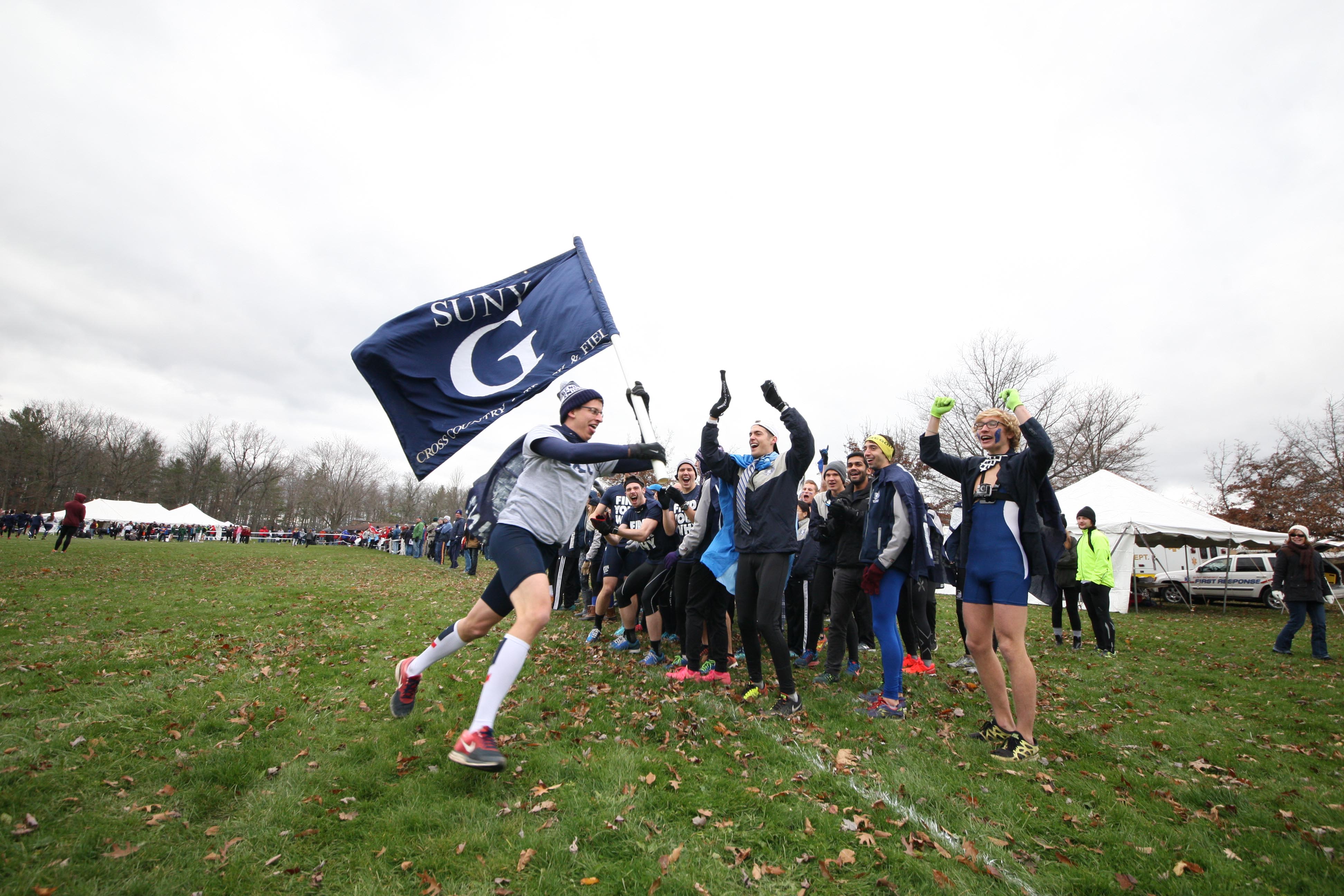 Cross-country team fans run with the SUNY G flag.