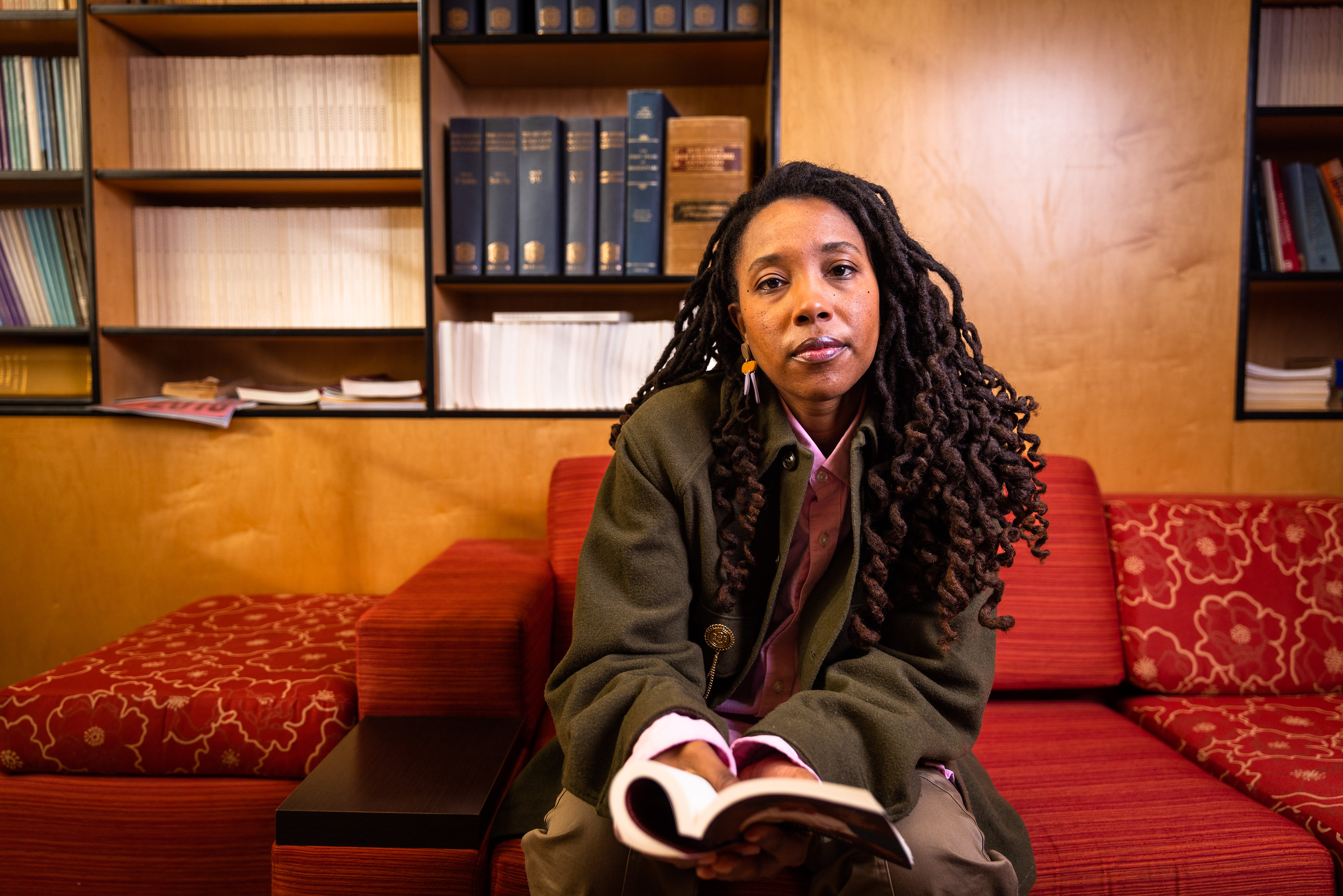 Kristen Gentry on a couch, holding a book.
