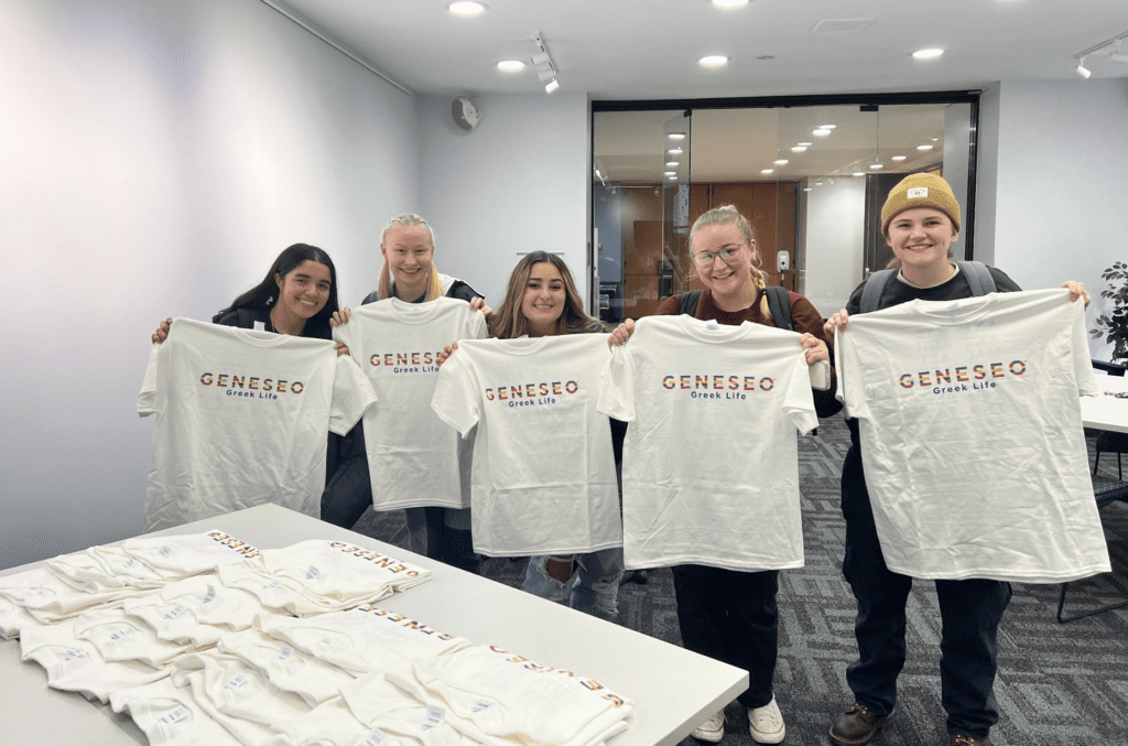 Screenshot 2023-11-13 at 11.55.10 AM Students holding Geneseo Greek Life t-shirts