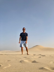 Jordan Daniel standing in sand dunes in Qatar.
