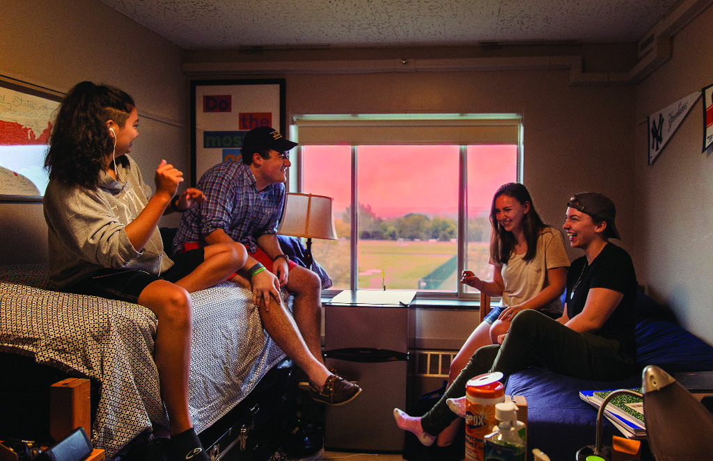 Student in a dorm room. The sun is setting outside behind them.