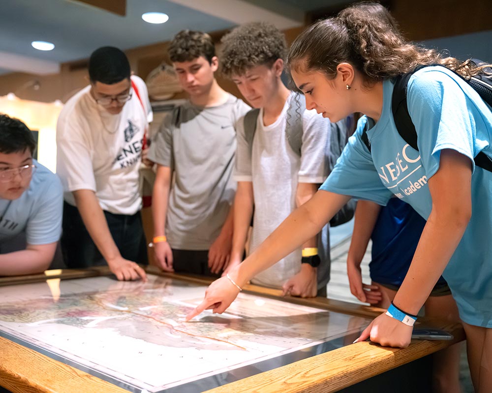 Students gathered around a table examine a map.