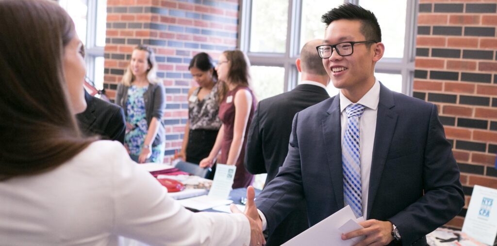 7D0A2734 (1) Two professionals in south hall shaking hands at a networking event.