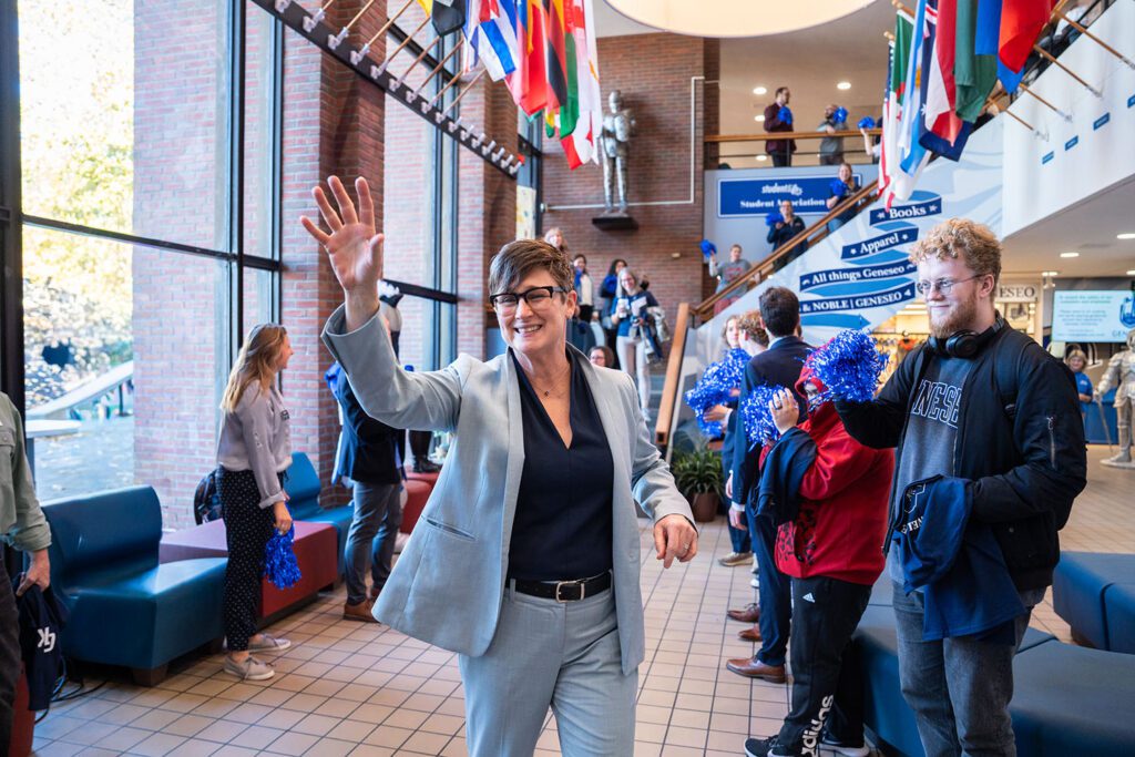 Photograph of President Melinda Treadwell waving to students in MacVittie College Union. 