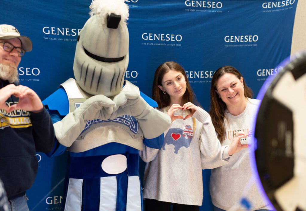 Mascot Victor E. Knight poses for a photo with a prospective student and her parents at Admitted Students Day.