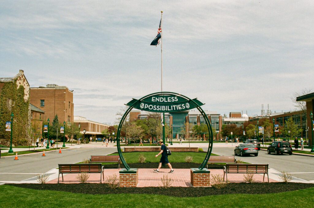 Image of college circle showing a semi-circle sculpture with a student walking past.