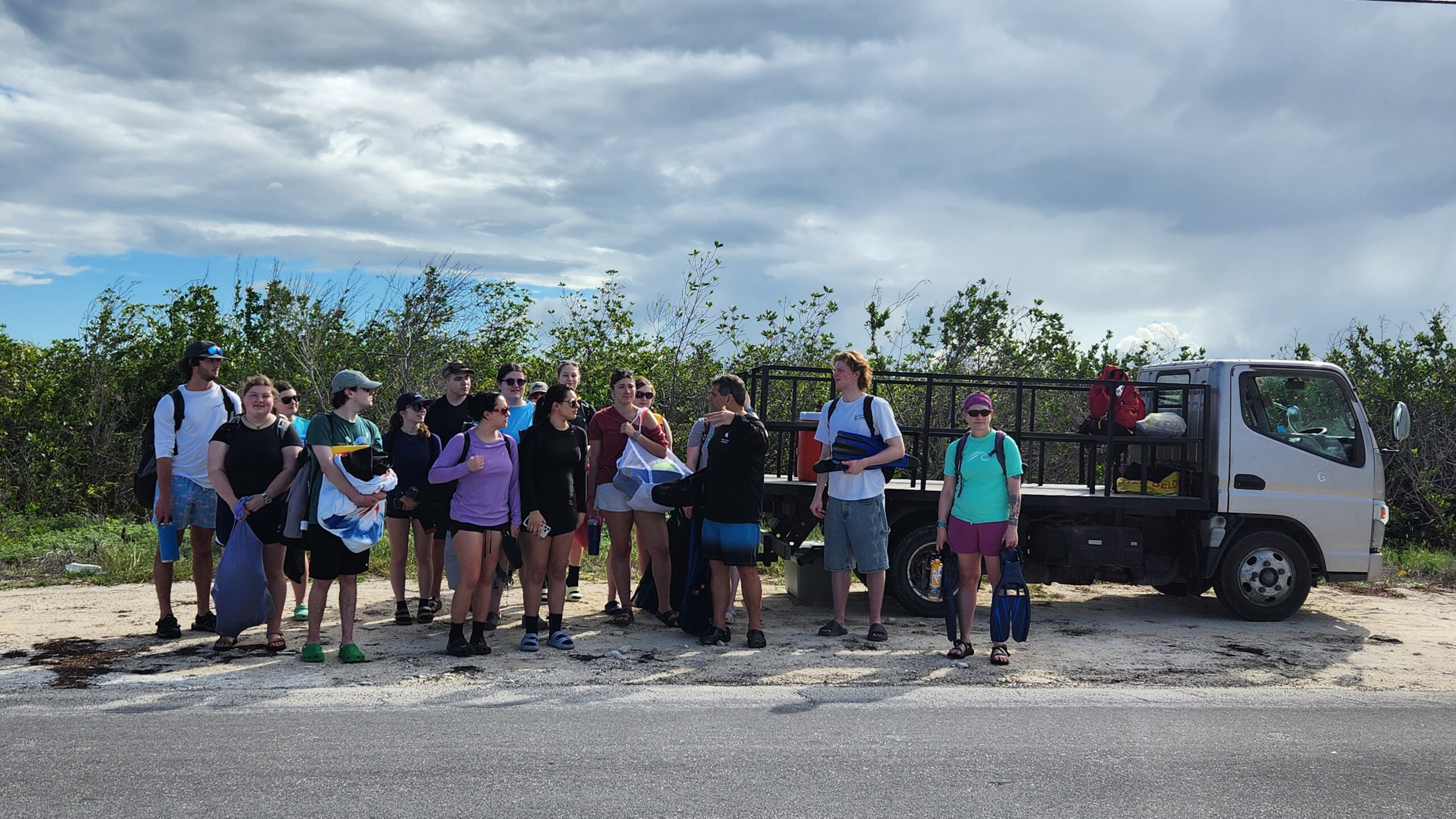 Students stand next to a pickup truck with snorkel gear.