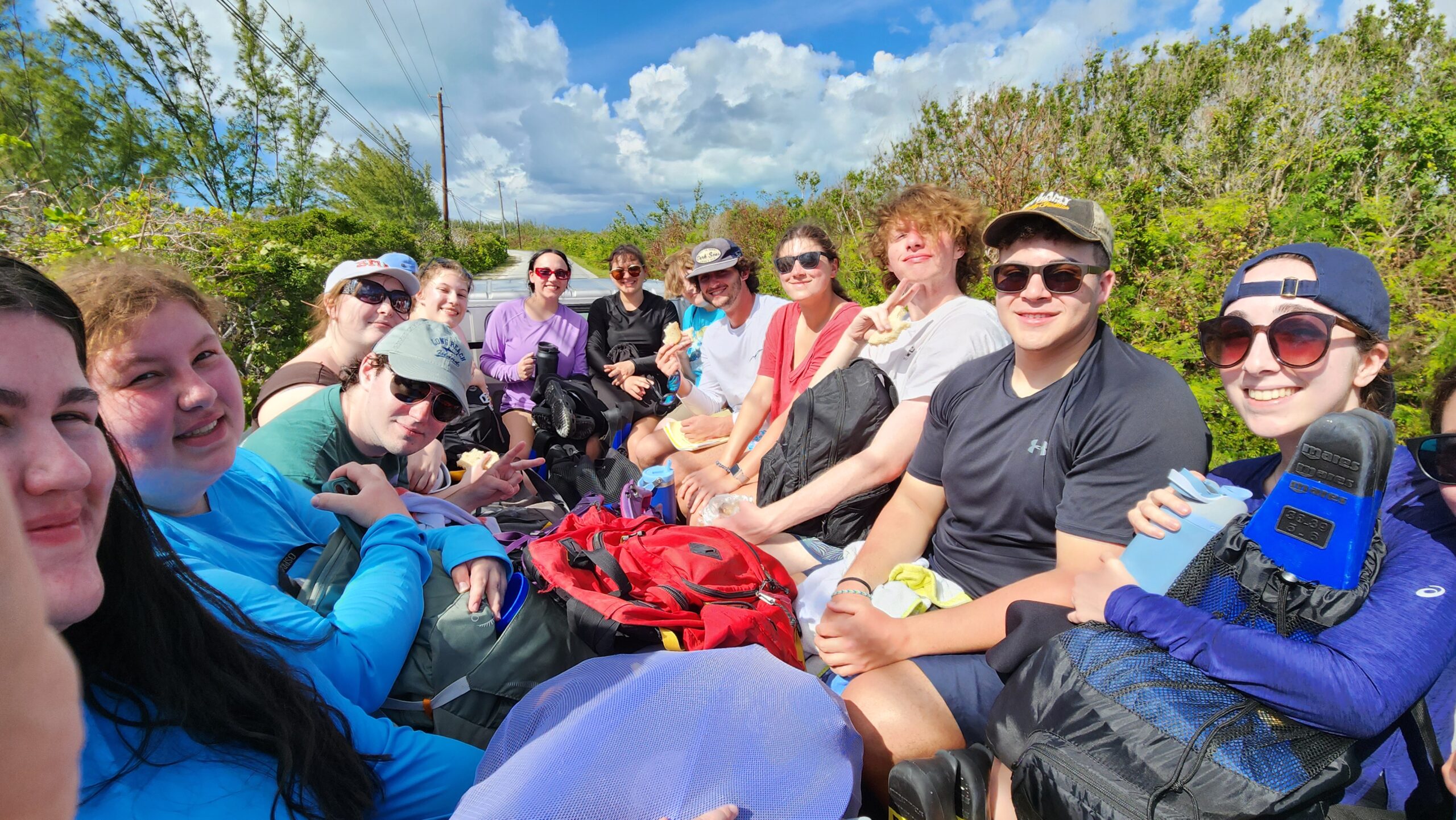 Students and faculty ride in the back of a pick up enroute to a shore site.
