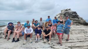 Class of students on rock at the shore.