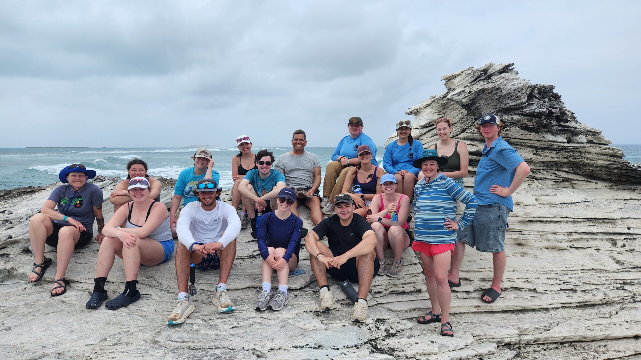 Class of students on rock at the shore.