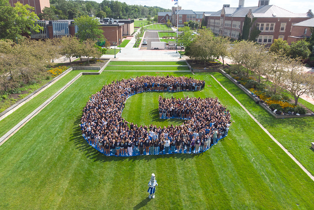 Students form the letter "G" on the college green.