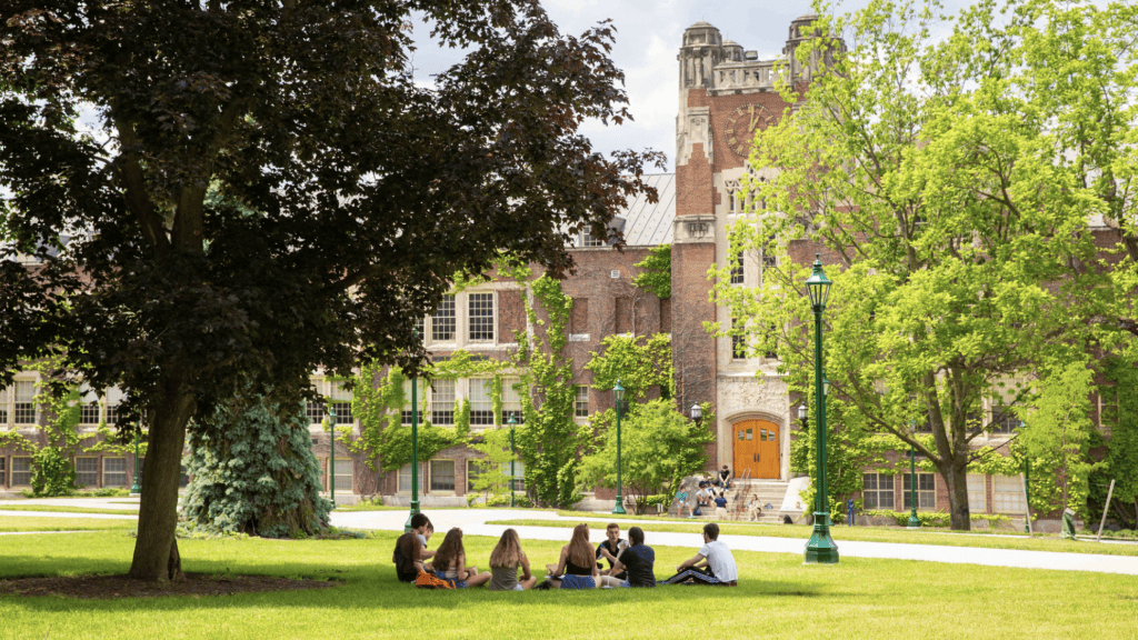 Sturgess Hall Students sitting in a circle on the lawn in front of Sturgess Hall
